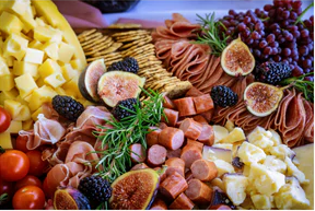 A charcuterie board overflowing with homegrown fruits as well as meats and cheeses.